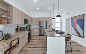A modern kitchen with wooden floors and a marble countertop.